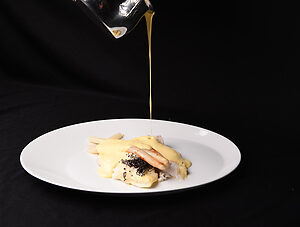 Sauce beurre blanc crémeuse versée en filet sur un filet de poisson blanc chaud, avec une texture onctueuse et brillante.