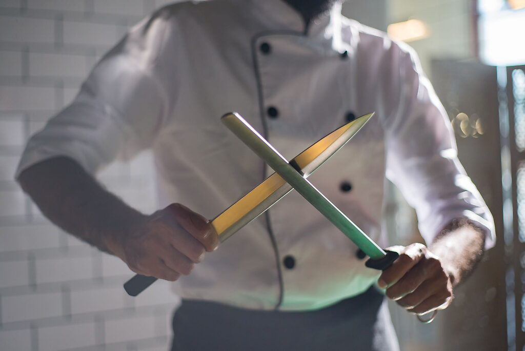 Chef affilant un couteau de cuisine professionnel avec un fusil d’affilage