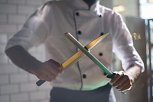 Chef affilant un couteau de cuisine professionnel avec un fusil d’affilage