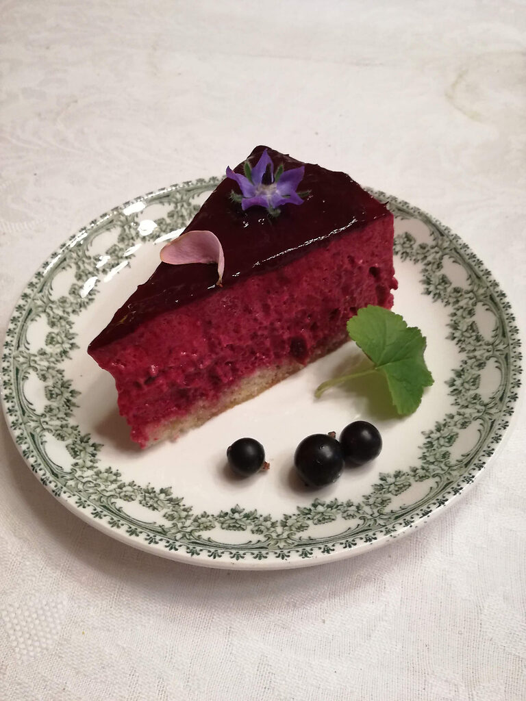 Portion de miroir au cassis sur sous-tasse, entremets avec glaçage brillant, décoré de cassis frais et feuille de cassissier