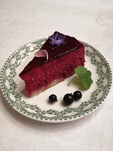 Portion de miroir au cassis sur sous-tasse, entremets avec glaçage brillant, décoré de cassis frais et feuille de cassissier