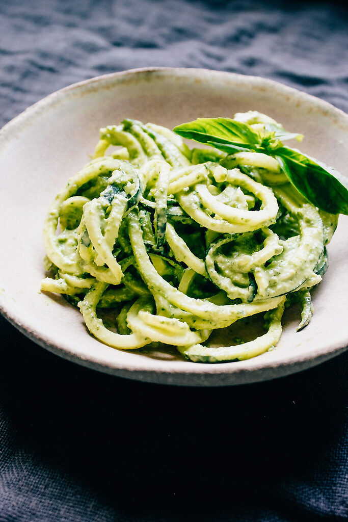Pâtes aux courgettes, mozzarella et basilic servies dans une assiette avec sauce crémeuse et morceaux de courgette.