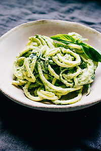 Pâtes aux courgettes, mozzarella et basilic servies dans une assiette avec sauce crémeuse et morceaux de courgette.