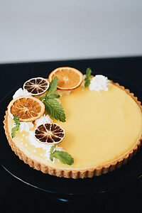 Tarte au citron décorée de meringues, citrons séchés et feuilles de menthe.
